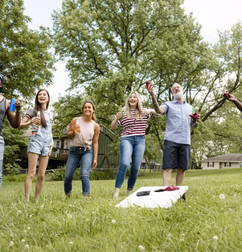 Amigos jugando cornhole en una fiesta de verano en el parque